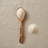 Abalone Shell Powder (Haliotis Spp.) | Create a luxurious, photorealistic product photograph featuring the original product naturally arranged in an elegant handcrafted wooden spoon on a soft, finely