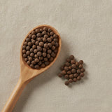 Allspice Berries Whole (Jamaican) (Pimenta Dioica) | Create a luxurious, photorealistic product photograph featuring the original product naturally arranged in an elegant handcrafted wooden spoon on a soft, finely