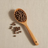 Allspice Whole (Mexican) (Pimento Officinalis) | Create a luxurious, photorealistic product photograph featuring the original product naturally arranged in an elegant handcrafted wooden spoon on a soft, finely