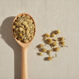 Arnica Flowers Whole (Heteroteca Inuloides) | Create a luxurious, photorealistic product photograph featuring the original product naturally arranged in an elegant handcrafted wooden spoon on a soft, finely