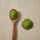 Barley Grass Powder (Hordeum Vulgare) | Create a luxurious, photorealistic product photograph featuring the original product naturally arranged in an elegant handcrafted wooden spoon on a soft, finely