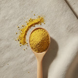 Bee Pollen Powder | Create a luxurious, photorealistic product photograph featuring the original product naturally arranged in an elegant handcrafted wooden spoon on a soft, finely