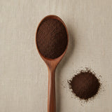 Black Walnut Hull Powder (Juglans Nigra) | Create a luxurious, photorealistic product photograph featuring the original product naturally arranged in an elegant handcrafted wooden spoon on a soft, finely