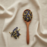 Butterfly Pea Flower Whole (Clitoria Ternatea) | Create a luxurious, photorealistic product photograph featuring the original product naturally arranged in an elegant handcrafted wooden spoon on a soft, finely