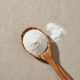 Calcium Citrate Powder (2-hydroxypropane-1,2,3-tricarboxylate) | Create a luxurious, photorealistic product photograph featuring the original product naturally arranged in an elegant handcrafted wooden spoon on a soft, finely