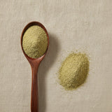 Cardamom Powder (Elettaria Cardamomum) | Create a luxurious, photorealistic product photograph featuring the original product naturally arranged in an elegant handcrafted wooden spoon on a soft, finely