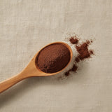 Carob Roasted Powder (Ceratonia Siliqua) | Create a luxurious, photorealistic product photograph featuring the original product naturally arranged in an elegant handcrafted wooden spoon on a soft, finely