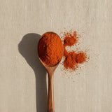 Cayenne Pepper Ground (100,000 HU) (Capsicum Frutescens) | Create a luxurious, photorealistic product photograph featuring the original product naturally arranged in an elegant handcrafted wooden spoon on a soft, finely