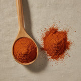 Cayenne Pepper Ground (130,000 HU) (Capsicum Annuum) | Create a luxurious, photorealistic product photograph featuring the original product naturally arranged in an elegant handcrafted wooden spoon on a soft, finely