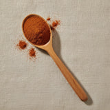 Cayenne Pepper Ground (40,000 HU) (Capsicum Annuum) | Create a luxurious, photorealistic product photograph featuring the original product naturally arranged in an elegant handcrafted wooden spoon on a soft, finely