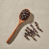 Cedar Berries Whole (Juniperus Monosperma) | Create a luxurious, photorealistic product photograph featuring the original product naturally arranged in an elegant handcrafted wooden spoon on a soft, finely