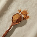 Ceylon Cinnamon Powder (Cinnamomum Verum) | Create a luxurious, photorealistic product photograph featuring the original product naturally arranged in an elegant handcrafted wooden spoon on a soft, finely