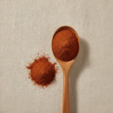 Chipotle Powder (Capsicum Annuum) | Create a luxurious, photorealistic product photograph featuring the original product naturally arranged in an elegant handcrafted wooden spoon on a soft, finely