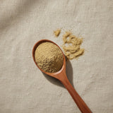 Coriander Seed Powder (Coriandrum Sativum) | Create a luxurious, photorealistic product photograph featuring the original product naturally arranged in an elegant handcrafted wooden spoon on a soft, finely