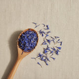 Cornflower Petals Whole (Centaurea Cyanus) | Create a luxurious, photorealistic product photograph featuring the original product naturally arranged in an elegant handcrafted wooden spoon on a soft, finely