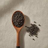 Cubeb Berry Whole (Piper Cubeba) | Create a luxurious, photorealistic product photograph featuring the original product naturally arranged in an elegant handcrafted wooden spoon on a soft, finely