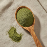 Dandelion Leaf Powder (Taraxacum Officinale) | Create a luxurious, photorealistic product photograph featuring the original product naturally arranged in an elegant handcrafted wooden spoon on a soft, finely