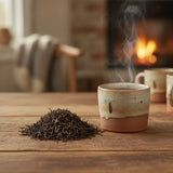 Darjeeling Black Tea (Camellia Sinensis) | Can you show this tea outside of the bag and bowl, on a table next to a hot tea cup in a rustic home.