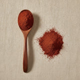 Dragon’s Blood Resin Powder (Daemonorops Draco) | Create a luxurious, photorealistic product photograph featuring the original product naturally arranged in an elegant handcrafted wooden spoon on a soft, finely
