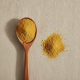 Fenugreek Seed Powder (Trigonella Foenum Graecum) | Create a luxurious, photorealistic product photograph featuring the original product naturally arranged in an elegant handcrafted wooden spoon on a soft, finely