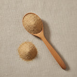 Flax Seed Meal (Linum Usitatissimum) | Create a luxurious, photorealistic product photograph featuring the original product naturally arranged in an elegant handcrafted wooden spoon on a soft, finely