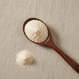 Garlic Powder (Allium Sativum) | Create a luxurious, photorealistic product photograph featuring the original product naturally arranged in an elegant handcrafted wooden spoon on a soft, finely