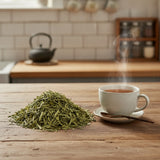 Green Tea Cut (Camillia Sinensis) | Can you show this tea outside of the bag and bowl, on a table next to a hot tea cup in a rustic home.