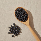 Juniper Berries Whole (German) (Juniperus Communis) | Create a luxurious, photorealistic product photograph featuring the original product naturally arranged in an elegant handcrafted wooden spoon on a soft, finely