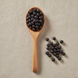 Juniper Berries Whole (Italian) (Juniperus Communis) | Create a luxurious, photorealistic product photograph featuring the original product naturally arranged in an elegant handcrafted wooden spoon on a soft, finely