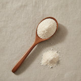 Lotus Seed Powder (Nelumbo Nucifera) | Create a luxurious, photorealistic product photograph featuring the original product naturally arranged in an elegant handcrafted wooden spoon on a soft, finely