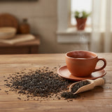 Lychee Black Tea (Camellia Sinensis) | Can you show this tea outside of the bag and bowl, on a table next to a hot tea cup in a rustic home.