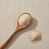 MacaXtra® Powder (Lepidium Meyenii) | Create a luxurious, photorealistic product photograph featuring the original product naturally arranged in an elegant handcrafted wooden spoon on a soft, finely