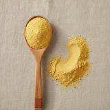 Mango Juice Powder (Mangifera Indica) | Create a luxurious, photorealistic product photograph featuring the original product naturally arranged in an elegant handcrafted wooden spoon on a soft, finely