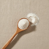 Mother-of-Pearl Shell Powder (Pteria Martensii) | Create a luxurious, photorealistic product photograph featuring the original product naturally arranged in an elegant handcrafted wooden spoon on a soft, finely