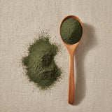 Nettle Leaf Powder (Urtica Dioica) | Create a luxurious, photorealistic product photograph featuring the original product naturally arranged in an elegant handcrafted wooden spoon on a soft, finely