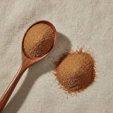 Nutmeg Ground (Myristica Fragrans) | Create a luxurious, photorealistic product photograph featuring the original product naturally arranged in an elegant handcrafted wooden spoon on a soft, finely