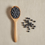 Oregon Grape Berries Whole (Mahonia aquifolium) | Create a luxurious, photorealistic product photograph featuring the original product naturally arranged in an elegant handcrafted wooden spoon on a soft, finely