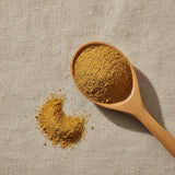 Orris Root Powder (Iris Germanica) | Create a luxurious, photorealistic product photograph featuring the original product naturally arranged in an elegant handcrafted wooden spoon on a soft, finely