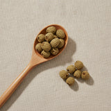 Palm Leaf Raspberry Fruit Whole (Rubus Chingii) | Create a luxurious, photorealistic product photograph featuring the original product naturally arranged in an elegant handcrafted wooden spoon on a soft, finely