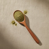Papaya Leaf Powder (Carica Papaya) | Create a luxurious, photorealistic product photograph featuring the original product naturally arranged in an elegant handcrafted wooden spoon on a soft, finely