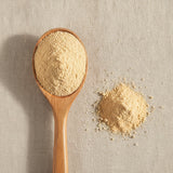 Peach Juice Powder (Prunus Persica) | Create a luxurious, photorealistic product photograph featuring the original product naturally arranged in an elegant handcrafted wooden spoon on a soft, finely