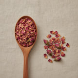 Pink Rose Buds & Petals Whole (Rosa Spp.) | Create a luxurious, photorealistic product photograph featuring the original product naturally arranged in an elegant handcrafted wooden spoon on a soft, finely