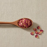 Pink Rose Petals (Rosa Canina) | Create a luxurious, photorealistic product photograph featuring the original product naturally arranged in an elegant handcrafted wooden spoon on a soft, finely