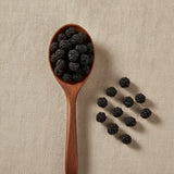Poke Berries Whole (Phytolacca Americana) | Create a luxurious, photorealistic product photograph featuring the original product naturally arranged in an elegant handcrafted wooden spoon on a soft, finely
