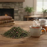 Pomegranate Green Tea (Camellia Sinensis) | Can you show this tea outside of the bag and bowl, on a table next to a hot tea cup in a rustic home.