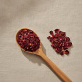Red Rose Petals (Rosa Canina) | Create a luxurious, photorealistic product photograph featuring the original product naturally arranged in an elegant handcrafted wooden spoon on a soft, finely