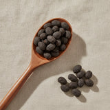 Saw Palmetto Berry Whole (Serenoa Repens) | Create a luxurious, photorealistic product photograph featuring the original product naturally arranged in an elegant handcrafted wooden spoon on a soft, finely