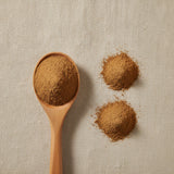 Tongkat Ali Powder (Eurycoma Longifolia Jack) | Create a luxurious, photorealistic product photograph featuring the original product naturally arranged in an elegant handcrafted wooden spoon on a soft, finely