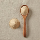 White Orchid Root Powder (Bletilla Striata) | Create a luxurious, photorealistic product photograph featuring the original product naturally arranged in an elegant handcrafted wooden spoon on a soft, finely